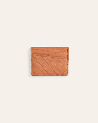 A small tan woven leather card holder with a diamond basketweave pattern, shown flat against a light cream background.