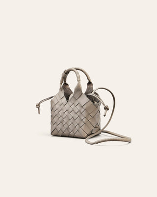 Woven handbag on a light beige background seen from the side