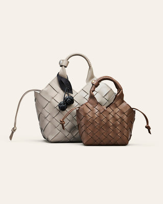 Two woven handbags, one gray and one brown, on a light beige background.