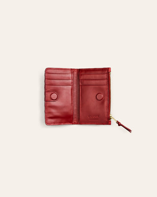 Red leather wallet with a zipper on a light beige background