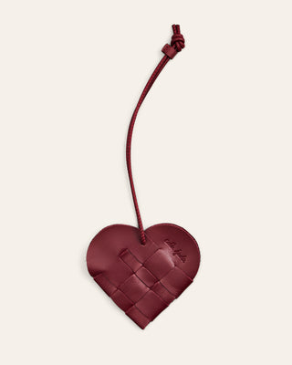 Cala Jade woven heart-shaped bag charm with a string on a beige background