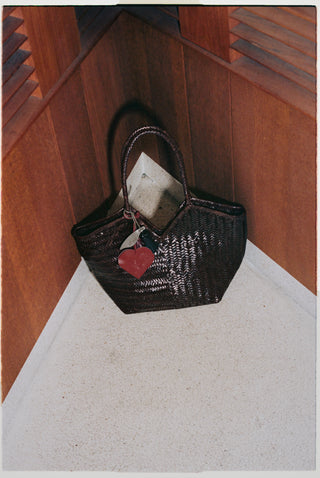 Cala Jade Black woven handbag with a red heart on a wooden surface