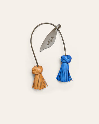 Cala Jade leather bag charm in yellow and blue shaped as a flower on a beige background