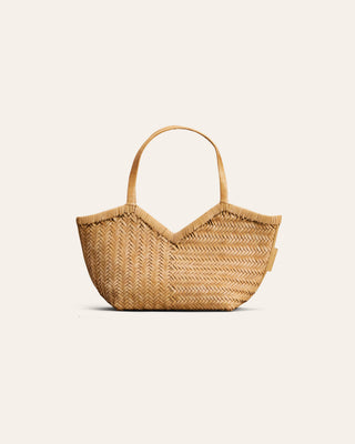 A small woven leather tote bag with a woven pattern, featuring two top handles and a small side tag, shown on a light cream background.