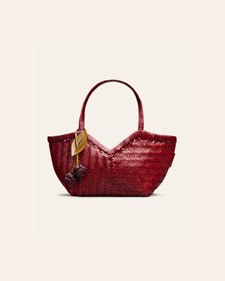 Cala Jade Humi S woven leather bag with a cherry bag charm attached on a beige bacground
