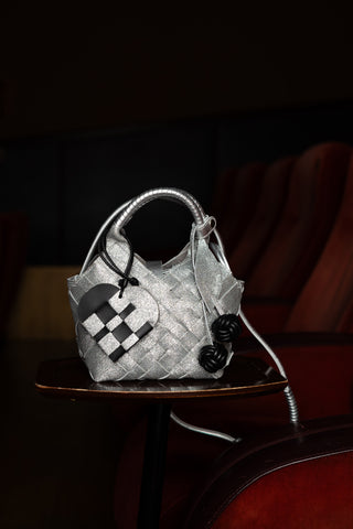 Cala Jade sparkling silver handbag with two bag charms attached on a dark background