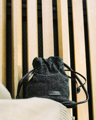 Black drawstring bag with a brand logo on a wooden surface