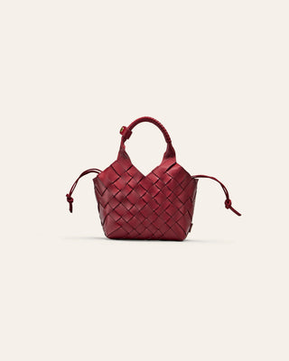 A small woven red leather bag on a beige background