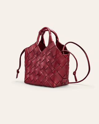 A red woven leather bag on a beige background seen from the side