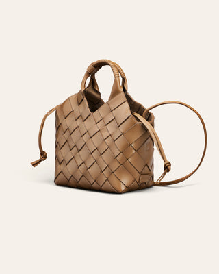 A small woven leather handbag in tan, featuring a structured basketweave pattern, a top handle with a decorative bead, and drawstring ties on the sides, shown against a solid off-white background.