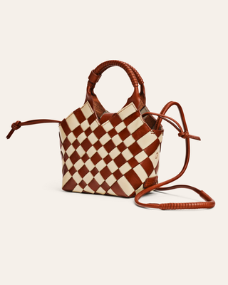 Checkered leather handbag with brown handles and strap on a light beige background
