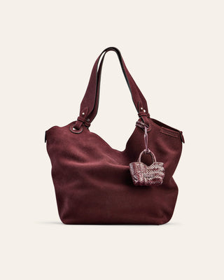 Brown handbag with a smaller woven handbag attached on a beige background