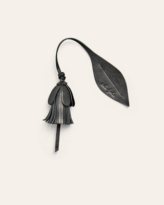 Black leather bag charm shaped as a flower on a beige backgrounf