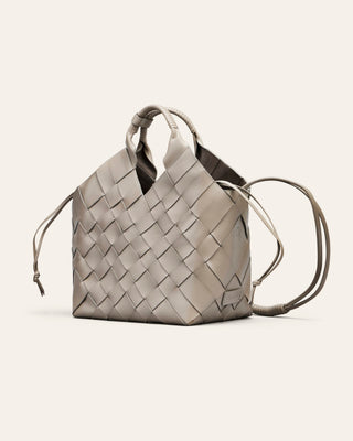 Cala Jade Misu Large in grey leather, woven handbag with drawstring on a light beige background
