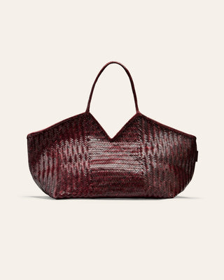 Woven burgundy handbag with a textured pattern on a light beige background