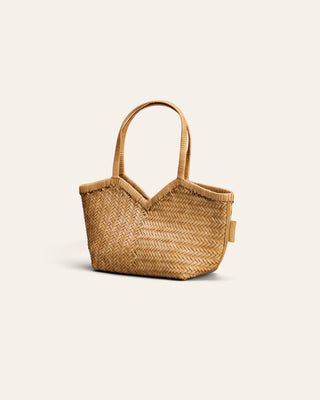 A small woven leather tote bag with a woven pattern, featuring two top handles and a small side tag, shown on a light cream background.