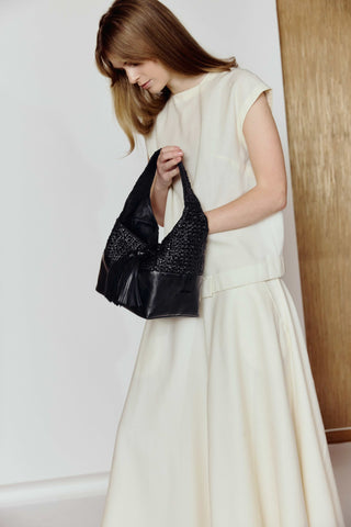 Woman holding a black handbag against a white background