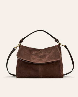 A brown suede shoulder bag on a beige background