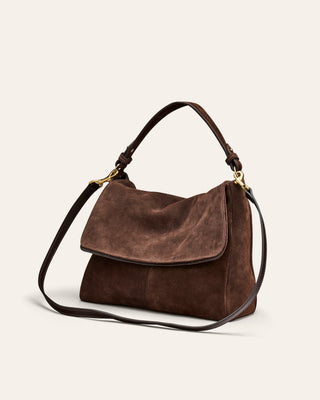 A brown suede shoulder bag on a beige background