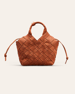 A small woven leather handbag in a warm cognac brown, featuring a structured basketweave pattern, a top handle, and thin drawstring ties on the sides, set against a solid off-white background.