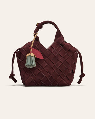 Woven brown handbag with decorative charm on a light beige background