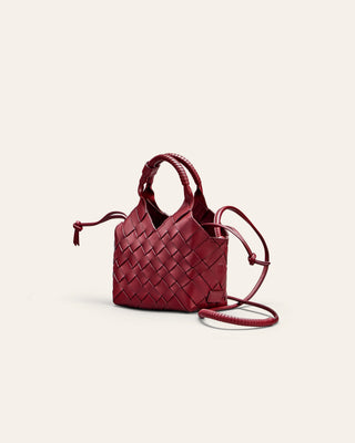 A small red woven shoulder bag seen from the side on a beige background