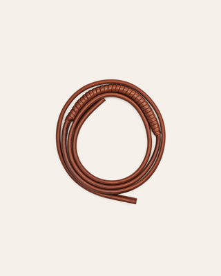 A brown leather shoulder strap on a beige background