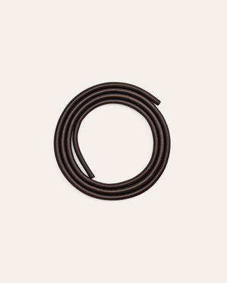 Dark brown colored leather shoulder strap on a beige background