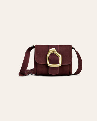 Burgundy suede shokuder bag on a beige bacground