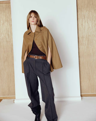 A woman standing in front of a white photo bakground with a brown leather belt