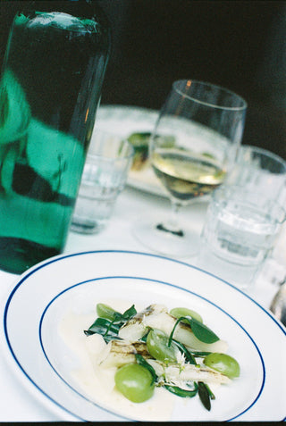 Dinner table setting with a plate of food, wine glasses, and a bottle.